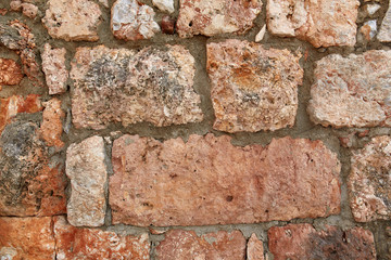 Old City walls. Stone Texture. Wall texture of ancient old brick stone. Outdoor exterior castle facade with destroyed uneven pattern of shabby rock. Grunge surface. Wall of the fortress