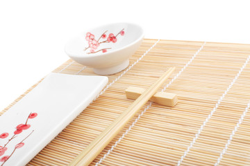 Sushi plates and chopsticks on bamboo mat