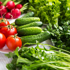Set of various organic ingredients for salad making: tomatoes, radish, cucumber, arugula, lettuce, side view. Healthy food. Close-up.