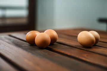 A group of fresh eggs laid on a wooden table and in an egg box