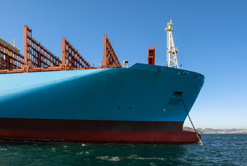 The bow of a huge container ship at anchored in the roads.