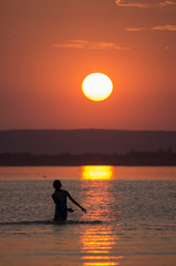 Children swim in the river at sunset.