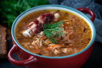 Soup in a plate on a dark wooden background. Russian cabbage soup.