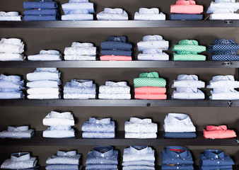 row of shirts on shelfs in men clothing store