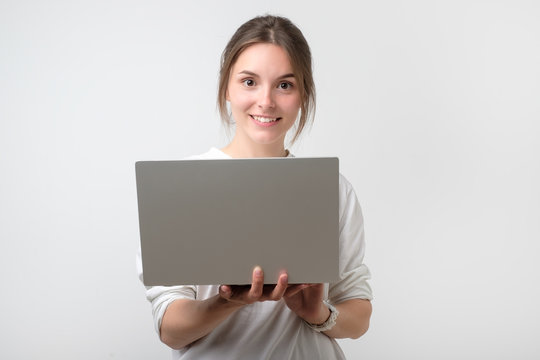 Smiling young european girl holding laptop computer
