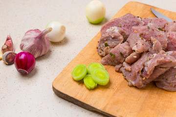 Raw pork kebab on wooden cutting board.