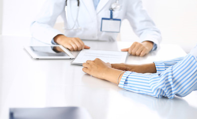 Doctor and patient talking and discussing health treatment while sitting at the desk. Medicine and health care concept