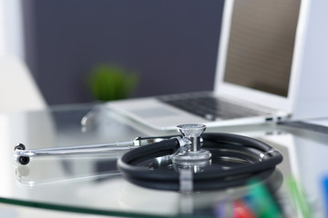 Obraz na płótnie Canvas Stethoscope, prescription medical form lying on glass table with laptop computer. Medicine or pharmacy concept. Medical tools at doctor working table