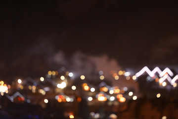 Blurred view of mountain village near forest in winter