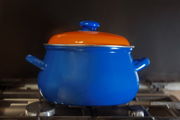 Blue pot with orange cap on gas stove side view