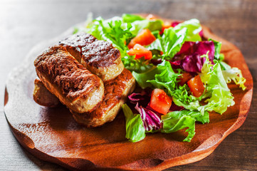 roasted sausages and various fresh mix salad leaves with tomato in plate on wooden table background