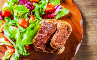 roasted sausages and various fresh mix salad leaves with tomato in plate on wooden table background