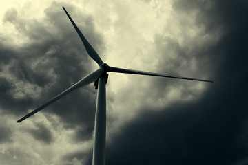 The wind generator is in dark stormy sky.