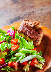 roasted sausages and various fresh mix salad leaves with tomato in plate on wooden table background