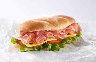 Salami sandwich made from bun, sliced ham and fresh letttuce, tomato and cheese. Healthy breakfast