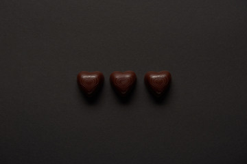 top view of sweet chocolate hearts on black background with copy space