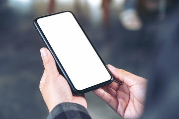 Mockup image of hands holding black mobile phone with blank white screen
