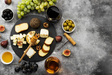 Snacks with wine - various types of cheeses, figs, nuts, honey, grapes on a gray background. Top view, copy space. Food background