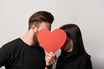 young couple in black with empty paper cut heart card