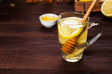 Autumn hot tea warming drink with ginger, honey and lemon in glass on wooden background