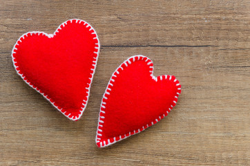 Wooden background with two red felt hearts, symbol of love. Good for Valentine's Day cards. Place for text.