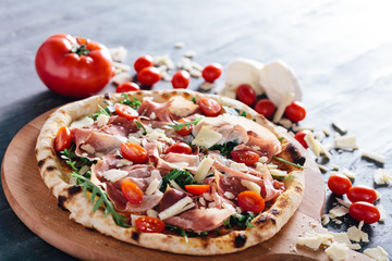 Pizza with ham, cheese, tomatoes and rocket salad .