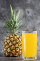 glass of pineapple juice with fresh fruits on grey bacground