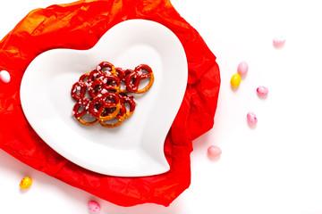 Idea for Valentine treats pretzel dip chocolate in ceramic heart shape plate on white background with copy space