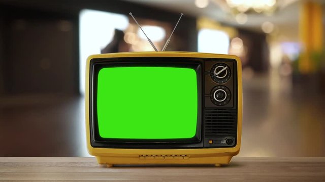 Yellow orange color old vintage retro Television on wood table with green screen .