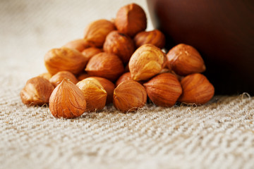 Peeled hazelnuts in a wooden, dark brown cup on a burlap cloth. Super Food, Raw.