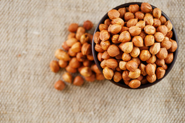 Peeled hazelnuts in a wooden, dark brown cup on a burlap cloth. Super Food, Raw.
