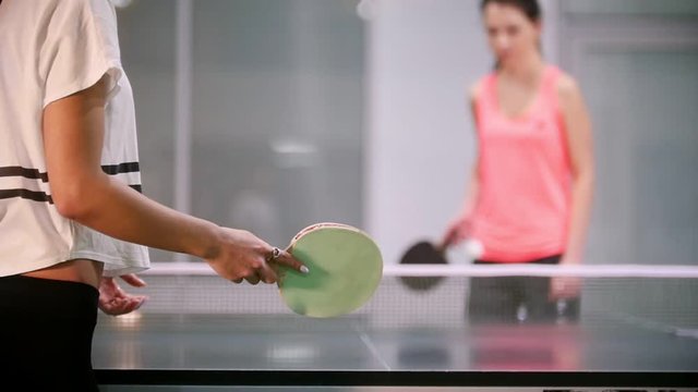 Ping pong playing. Young woman innings the ball, her opponent fails and the woman catches the ball with a hand
