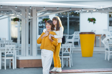 Mother and little daughter having fun in a park on a nice sunny day.wearing casual clothes yellow and white color