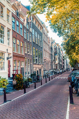Street scene from Amsterdam with typical architecture of row of buildings alongside canal with non recognizable people in the background
