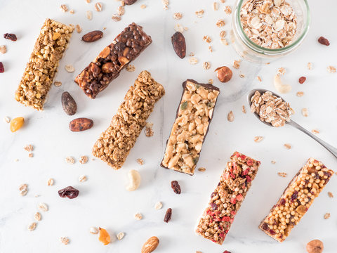 Granola bar with copy space. Set of different granola bars on white marble table. Shallow DOF. Top view or flat lay.