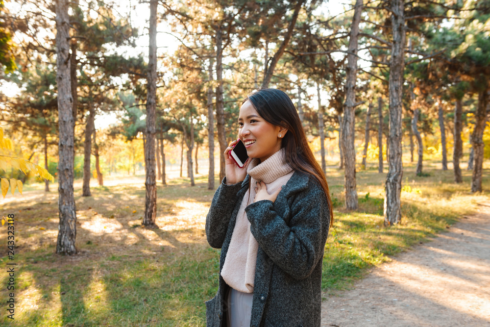 Wall mural smiling young asian woman wearing coat walking