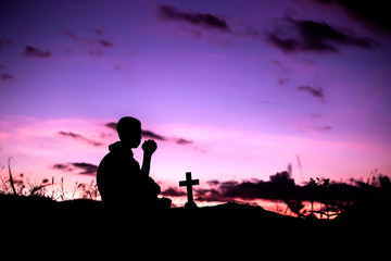 Fototapeta na wymiar Boy sitting and praying with light of sunset , christian silhouette concept.
