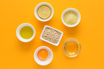 Obraz na płótnie Canvas Fresh ingredients for homemade effective acne remedies on yellow background. Honey, sea salt, egg yolk, olive oil, oat, lemon and aloe. Flat lay. Copy space