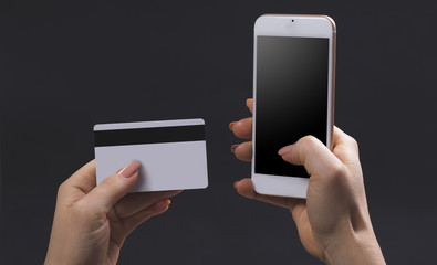female hands hold mobile and bank card