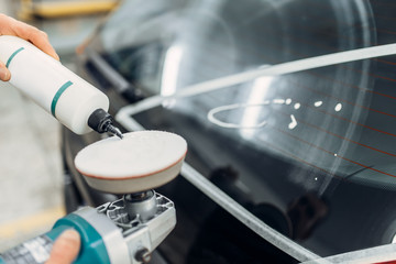 Worker polishing rear window of the car