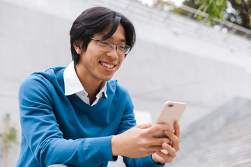 Smiling young asian man talking on mobile phone