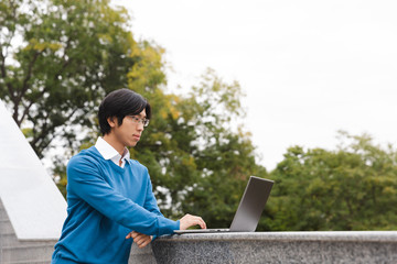 Smiling asian business man using laptop computer