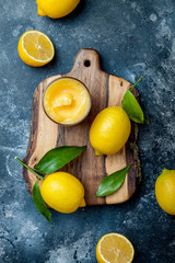 Lemon curd in a glass jar with fresh lemons. Top view