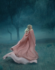 fairy-tale witch with blond hair who runs in a dark and dense mysterious forest full of white mist,...