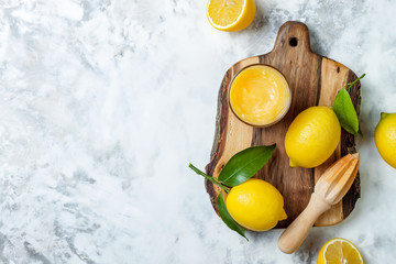 Lemon curd in a glass jar with fresh lemons. Top view