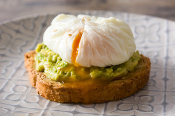 Close up avocado toast with poached egg on wooden table