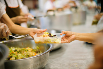 Hands of volunteers serves free food to the poor and needy in the city