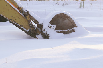 The old thrown excavator in a snowdrift in the winter.