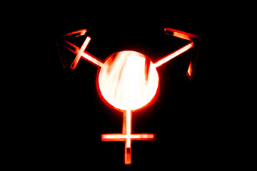 Image of a transgender symbol on a black background. Bokeh effect