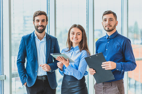 Three businessmen are in the office dressed in business clothes. During this one in the hands of a folder with documents, in another tablet.